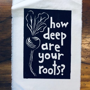 Puede incluir: Impresión en blanco y negro sobre tela con un nabo blanco y hojas y el texto "how deep are your roots?"