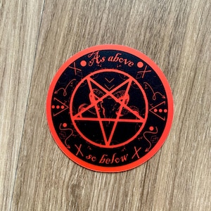 May include: A round sticker with a black background and a red border. The sticker features a red pentagram with a goat's head inside. The text "As above, so below" is written around the edges in red.