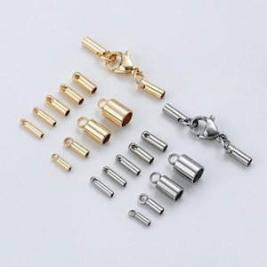 May include: A selection of gold and silver jewellery clasps and end caps. The clasps have lobster claw closures. End caps are cylindrical with a loop or hole for attaching to jewellery. The components are arranged on a white surface.