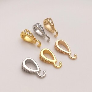 May include: Five pendant bails with a teardrop shape and a small loop at the top. The bails are decorated with clear rhinestones and come in silver, gold, and rose gold.