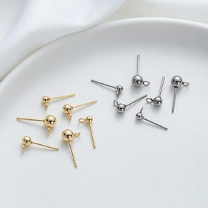 Puede incluir: Primer plano de hallazgos de pendientes con cabezas redondas. Los hallazgos están disponibles en dos colores: oro y plata.