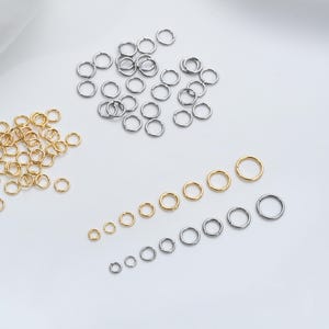 Könnte beinhalten: Sortiment aus silbernen und goldenen Sprungringen in verschiedenen Größen. Die Sprungringe sind in Reihen von klein nach groß angeordnet.