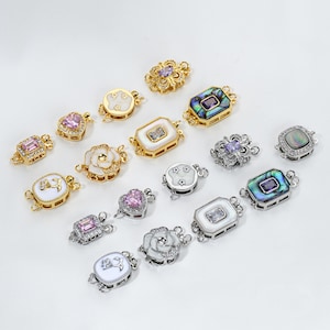 May include: An assortment of decorative jewelry clasps in various shapes and designs. The clasps feature gold and silver metalwork, with accents of white, pink, and purple gemstones, and mother-of-pearl inlays. The clasps are designed for jewelry making.