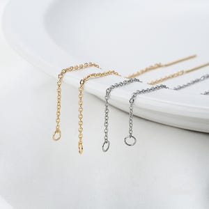 Puede incluir: Dos pares de cadenas extensoras para pendientes. Un par es dorado y el otro es plateado.