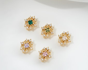 May include: Five gold-colored, ornate stud earrings with square-cut gemstones in green, olive, white, lavender, and pink. Each earring features a filigree design with small, clear accent stones. The earrings are displayed on a white surface.