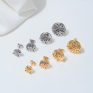 Può includere: Un assortimento di orecchini a bottone in tonalità oro e argento. Gli orecchini hanno un design circolare con piccole perforazioni. Gli orecchini sono esposti su una superficie bianca con un panno bianco sullo sfondo.