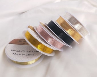 May include: Five spools of wire in different colors: gold, silver, black, rose gold, and copper. The spools are labeled "Tamaño/Size: 0.4mm Made in China".