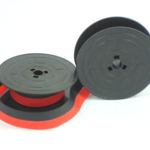 Peut inclure: Deux bobines noires de ruban de machine à écrire avec un ruban rouge et noir attaché.