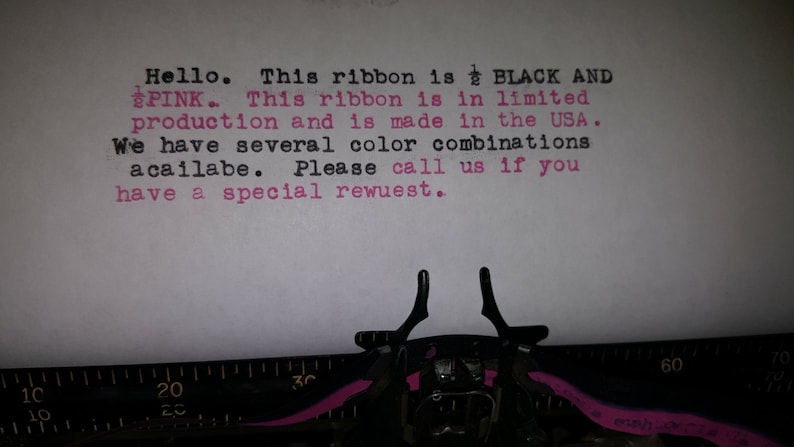 May include: Close-up of a typewriter with a typed message: "Hello. This ribbon is BLACK AND PINK. This ribbon is in limited production and is made in the USA. We have several color combinations acailabe. Please call us if you have a special rewuest."