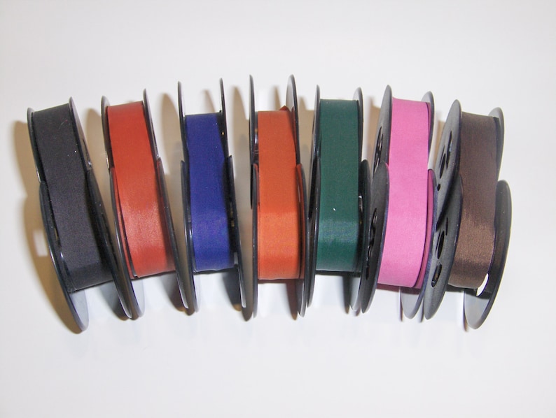 May include: Eight spools of typewriter ribbon in various colors, including black, red, blue, orange, green, pink, and brown.
