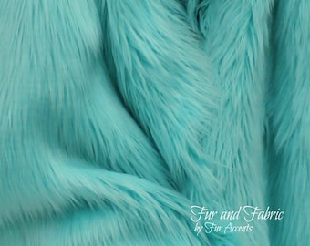 May include: Close-up of a soft, turquoise blue faux fur fabric. The fabric has a long pile and is very plush.  Fur and Fabric by Fur Accents.