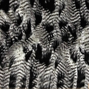 May include: Black and white faux fur fabric with a chevron pattern. The fabric is soft and fluffy, and it would be perfect for making a variety of projects, such as coats, jackets, hats, and scarves.