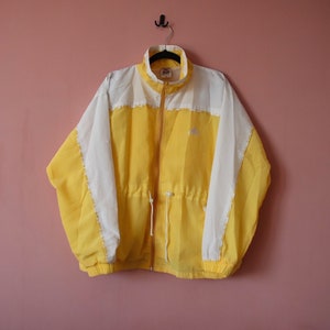 May include: A yellow and white windbreaker jacket with a zip fastening and a drawstring at the waist.