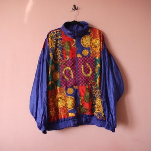 May include: A blue, red, green and gold patterned jacket with a zip closure. The jacket has a geometric design with a variety of shapes and symbols.