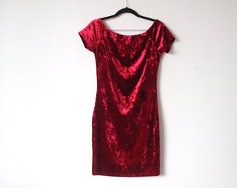 Könnte beinhalten: Ein rotes Samtkleid mit offener Schulter und kurzen Ärmeln, das an einem schwarzen Kleiderbügel hängt.