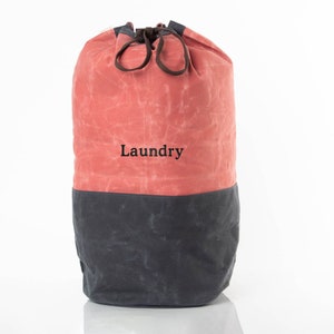 May include: A red and gray canvas laundry bag with a drawstring closure. The bag has the word "Laundry" printed on the front.