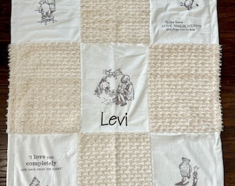 May include: A white and beige patchwork baby blanket with Winnie the Pooh characters and quotes. The blanket has a personalized name, "Levi", in the center.