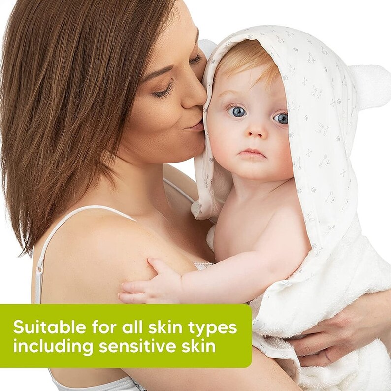 May include: A baby wearing a white hooded towel with bear ears is held by a person. The towel has a subtle floral pattern. The text "Suitable for all skin types including sensitive skin" is displayed in a green rectangle.