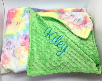 May include: A green minky baby blanket with a tie-dye pattern on the reverse side. The blanket is personalized with the name "Kiley" embroidered in blue thread.