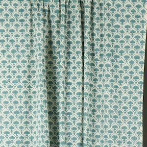 May include: A pair of floor-length curtains featuring a repeating teal and white floral pattern. The fabric is gathered at the top with a rod pocket header, creating vertical folds that extend down the length of the panels to the bottom hem.