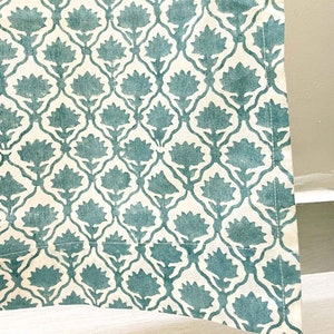 May include: A textile fabric featuring a repeating pattern of teal floral motifs arranged within a white lattice structure. The design consists of stylized flowers with pointed petals connected by thin, curved lines, creating a symmetrical grid.