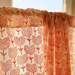May include: A semi-sheer curtain panel featuring a repeating pattern of red tulip-shaped flowers made of small dots on a light cream-colored fabric. The curtain is gathered at the top on a rod, allowing light to filter through the textured material.