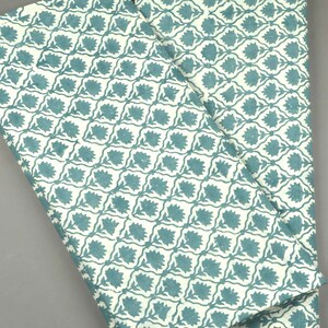 May include: Two folded pieces of fabric featuring a repeating pattern of teal floral motifs set within a white grid. The design consists of stylized flowers centered in each diamond-shaped section, creating a consistent geometric and botanical print.