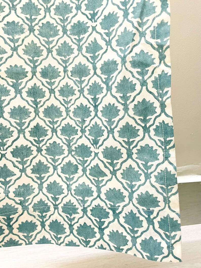 May include: A textile fabric featuring a repeating pattern of teal floral motifs arranged within a white lattice structure. The design consists of stylized flowers with pointed petals connected by thin, curved lines, creating a symmetrical grid.