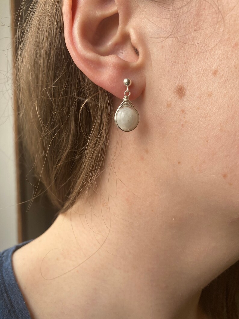 May include: A pair of silver wire wrapped earrings with white moonstone stones.