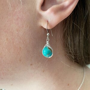 May include: Silver earrings with a turquoise stone wrapped in wire.