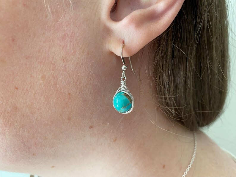 May include: Silver earrings with a turquoise stone wrapped in wire.