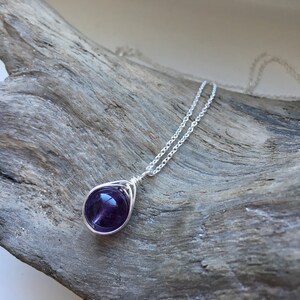 May include: A silver chain necklace with a purple amethyst gemstone pendant wrapped in silver wire.