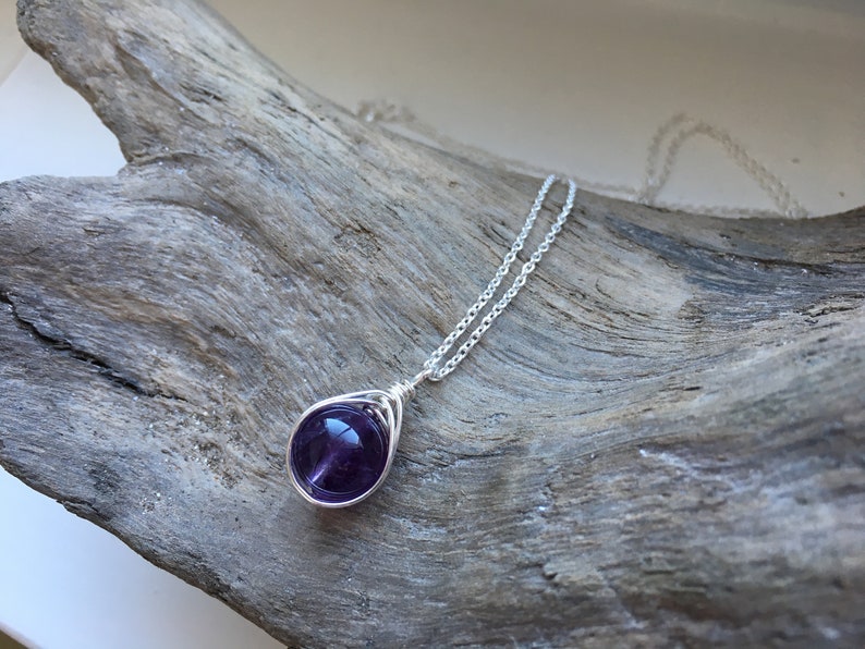 May include: A silver chain necklace with a purple amethyst gemstone pendant wrapped in silver wire.