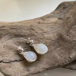 May include: A pair of silver wire wrapped earrings with round moonstone gemstones.