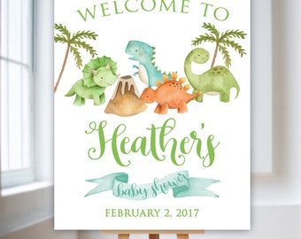 Könnte beinhalten: Willkommen zur Babyparty von Heather Schild mit einer grünen, blauen und orangefarbenen Dinosaurier-Illustration und einem grünen Vulkan. Das Datum 2. Februar 2017 ist unter den Dinosauriern gedruckt.