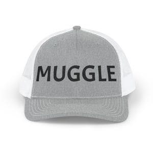May include: A gray trucker hat with a white mesh back and a curved brim. The word "MUGGLE" is printed in bold black letters across the front of the hat.