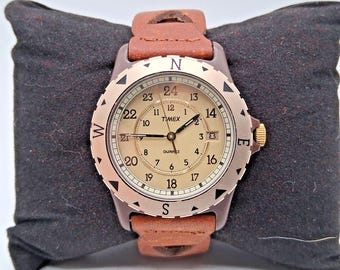 New  The Vintage Timex Safari Watch from 1989 features a classic brown round dial with Arabic numerals and a date indicator.