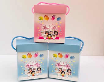 May include: Three gift boxes with colourful balloon designs and Arabic text. The boxes are pink, light blue, and light blue. The boxes have a string handle.