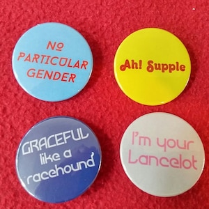 May include: Four round buttons with different messages. The top left button is light blue with red text that says "No Particular Gender". The top right button is yellow with red text that says "Ah! Supple". The bottom left button is dark blue with white text that says "Graceful like a racehound". The bottom right button is light gray with pink text that says "I'm your Lancelot".