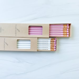 May include: Two boxes of six pencils each. The pencils are pink and white with gold lettering that reads "Chaos Coordinator". The boxes are brown with white text that reads "The Good Teacher Co."
