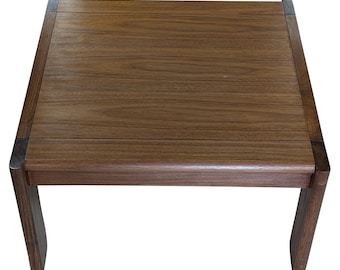 May include: A dark brown wooden coffee table with a rectangular top and four legs. The table has a simple, mid-century modern design.