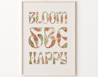 Op de afbeelding: Een witte ingelijste print met de tekst "Bloom Be Happy" in een bloemenpatroon.