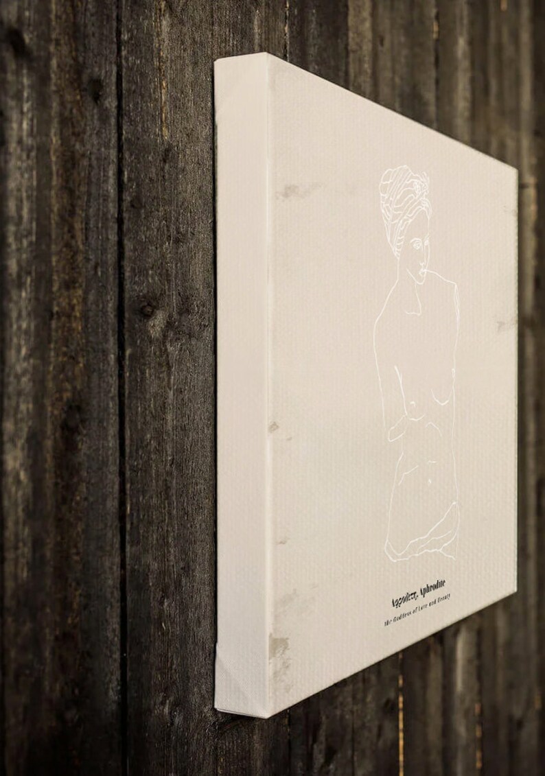 May include: A white canvas print with a line drawing of a woman's torso. The text "Ageless, Undressed" is printed below the drawing. The text "The tradition of love and beauty" is printed below the first line of text.