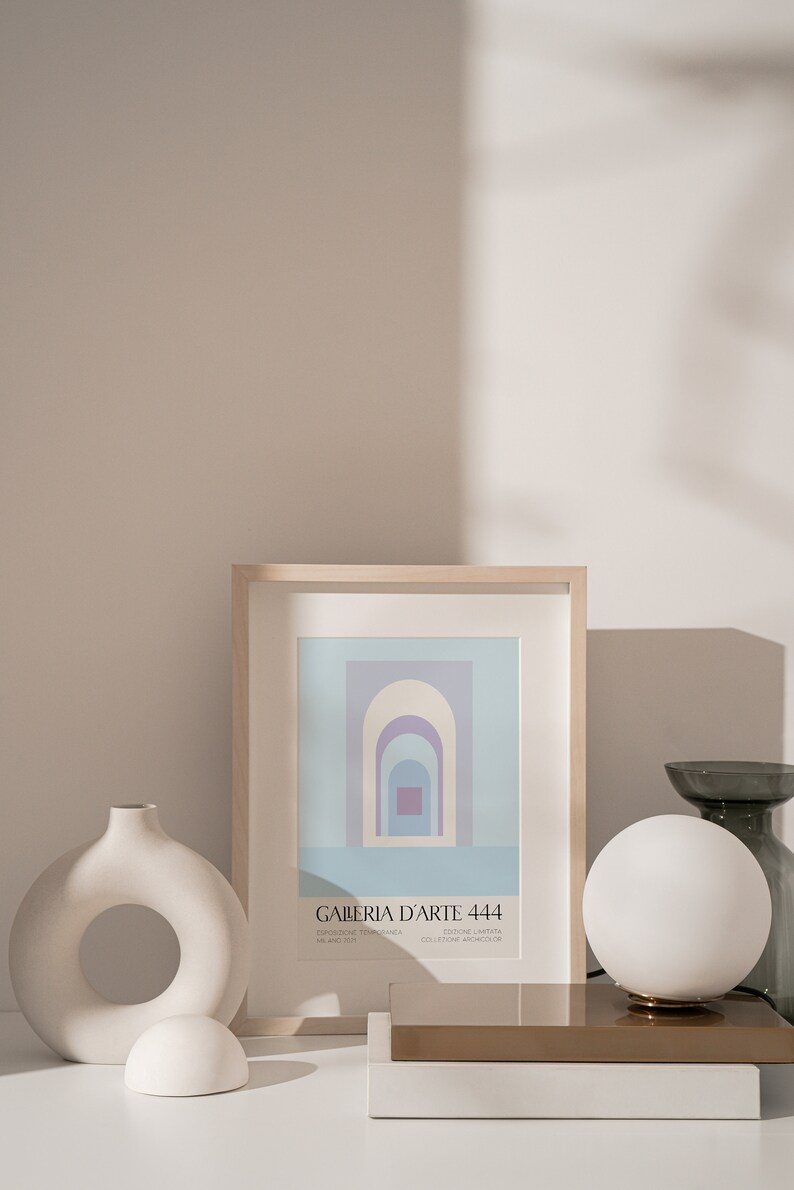 Peut inclure: Une impression encadr&eacute;e avec un motif abstrait bleu et violet. L'impression est intitul&eacute;e "Galeria D'Arte 444" et comprend le texte "Edizione Limitata" et "Collezione Archivos 08". L'impression est affich&eacute;e sur une surface blanche avec un vase blanc, une sph&egrave;re blanche et une lampe dor&eacute;e et blanche.