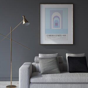 Peut inclure: Un canap&eacute; blanc avec des coussins &agrave; motifs noir et blanc et un coussin noir. Un lampadaire dor&eacute; se trouve dans le coin de la pi&egrave;ce. Un poster encadr&eacute; avec un design g&eacute;om&eacute;trique et le texte "GALLERIA D'ARTE 444" est accroch&eacute; au mur.