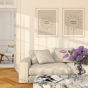 Puede incluir: Dos impresiones enmarcadas con el texto "Energy Givers" y "Energy Takers" en una sala de estar con un sof&aacute; blanco, una mesa de caf&eacute; y un jarr&oacute;n de flores moradas.