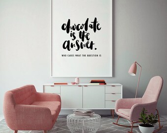 May include: A framed print with the text "Chocolate is the answer. Who cares what the question is" in black script. The print hangs above a white cabinet, with two pink armchairs and a small white table in front.