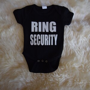 May include: Black baby onesie with white text that reads "RING SECURITY".