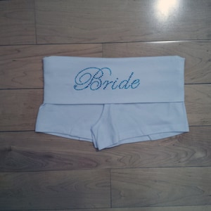 May include: White cotton underwear with a blue rhinestone "Bride" design.