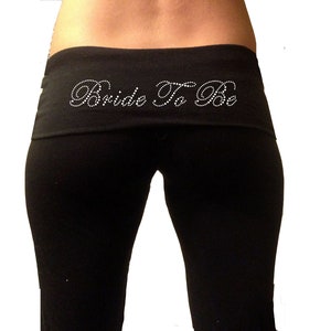 May include: Black yoga pants with a wide waistband that says "Bride To Be" in white rhinestones.
